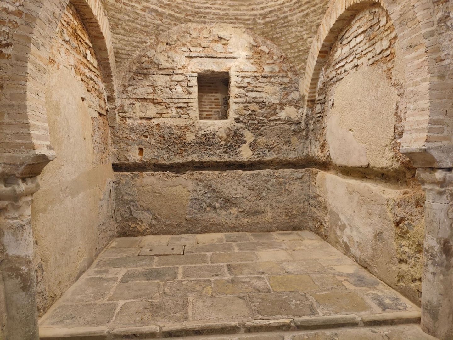 Historischer, gewölbter Raum mit freigelegtem Mauerwerk und Steinboden
