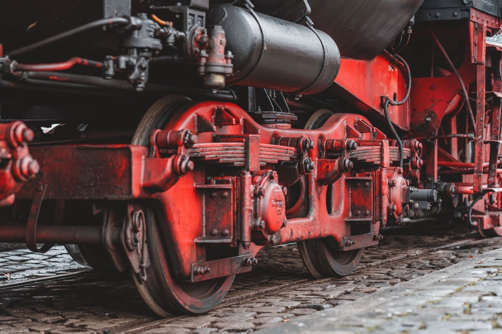 Nahaufnahme des roten Fahrwerks einer historischen Lokomotive auf Gleisen